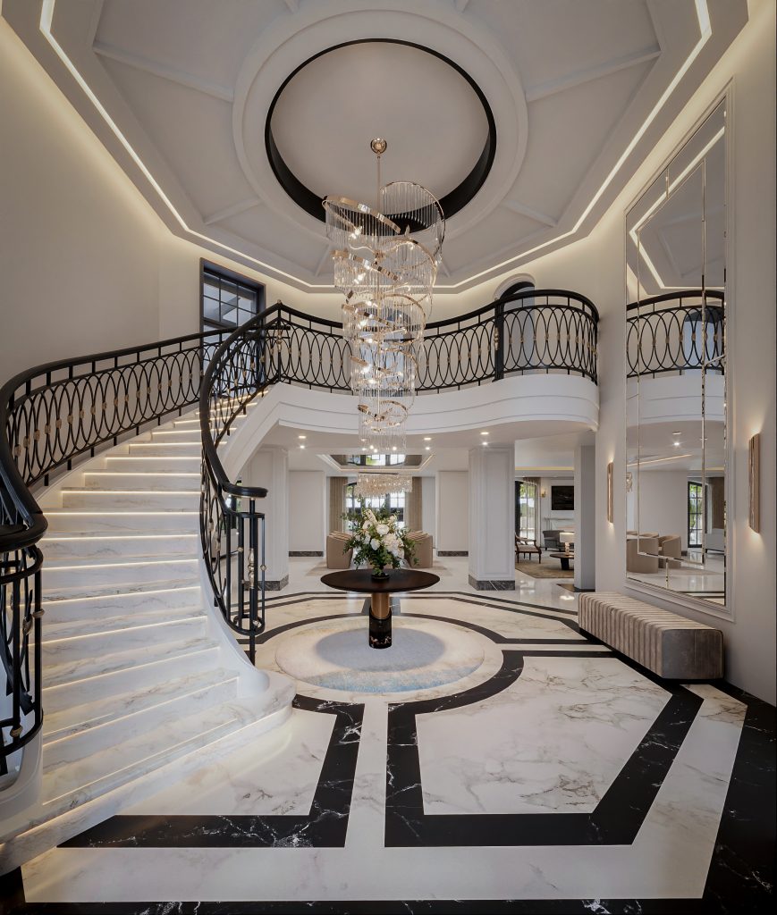 Double-height entrance hall with a sweeping marble staircase, wrought-iron balustrade and cascading chandelier in a La Zagaleta villa