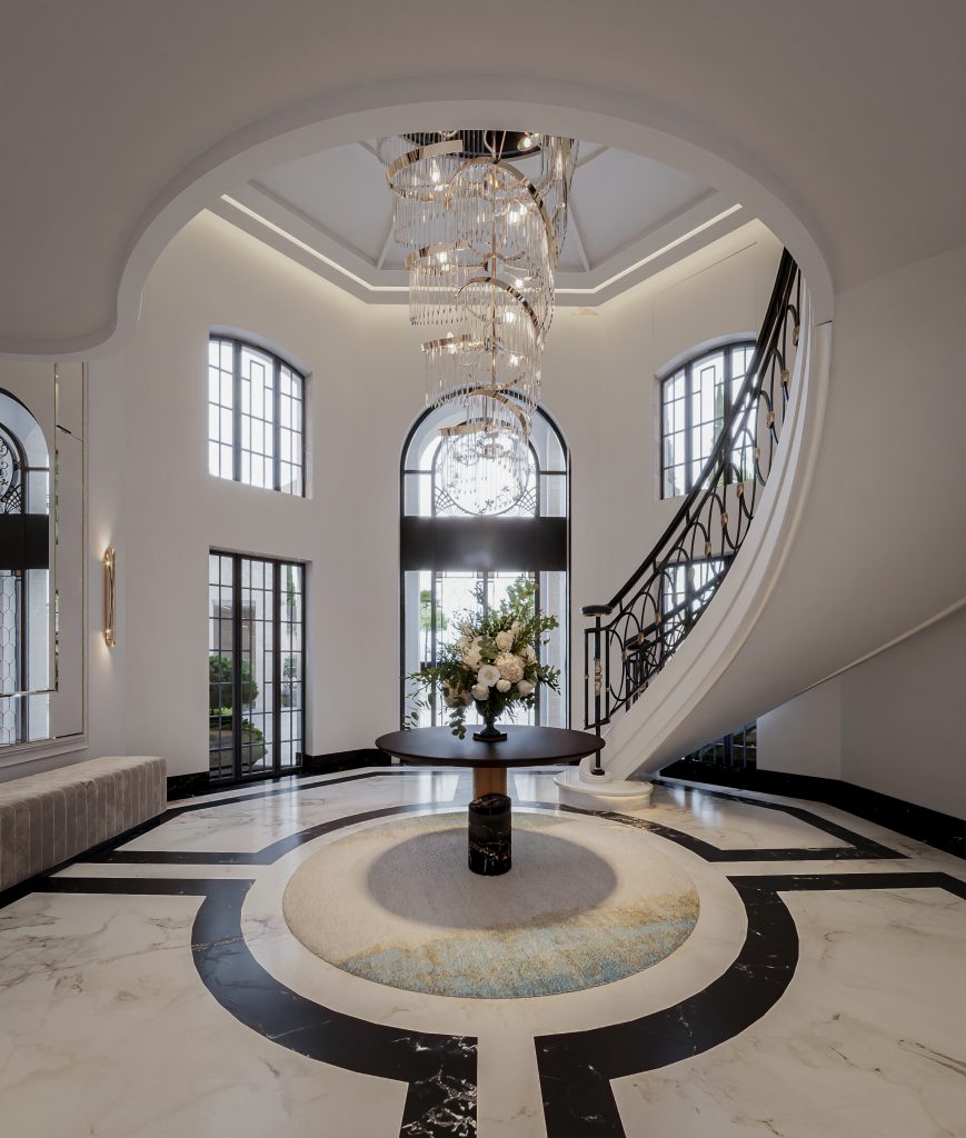 Circular entrance hall with arched windows, a crystal chandelier and a curved staircase in a La Zagaleta villa